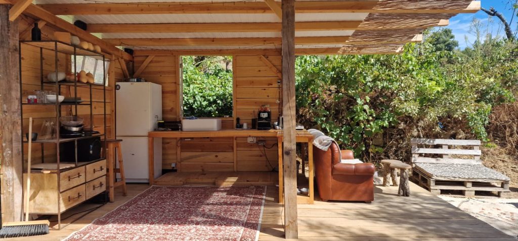 Cozinha exterior moderna para churrasco e área de convívio em madeira.