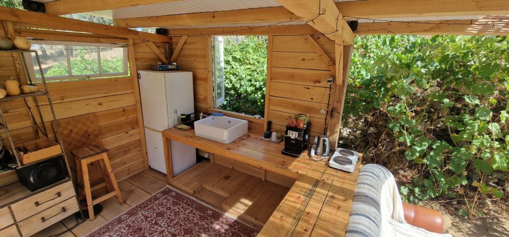 Cozinha exterior moderna para churrasco e área de convívio em madeira.