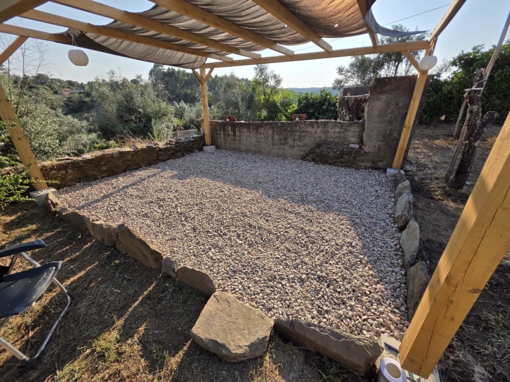 Construção de pérgola em madeira sobre pátio com piso de pedra.