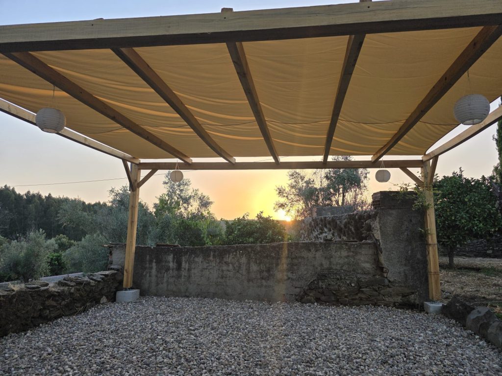 Construção de pérgola em madeira sobre pátio com piso de pedra.